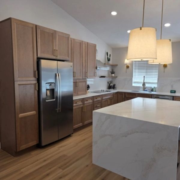 Modern kitchen with brown wood cabinets and white waterfall edge countertops.