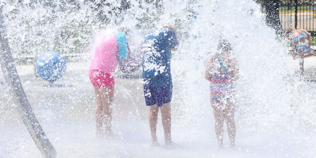 Children playing and enjoying water splashes at a splash pad.
