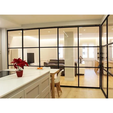 Modern kitchen and living room separated by black-framed glass walls.