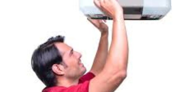 Man installing or adjusting a ceiling-mounted projector indoors.