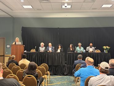 the event of speakers from behind the crowd all lined up on stage with microphones. One at podium