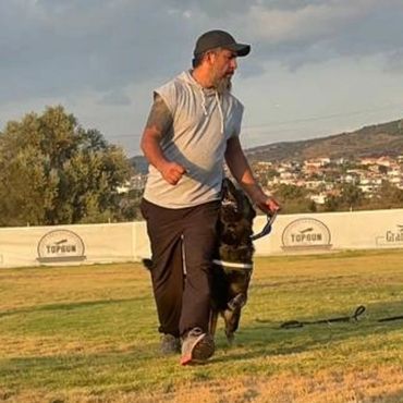 İDARECİSİNİN YÜZÜNE ODAKLI SOL TARAFINDA YÜRÜYEN BİR ALMAN ÇOBAN KÖPEĞİ