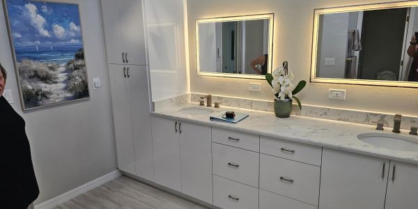 Modern bathroom with double sinks and illuminated mirrors.