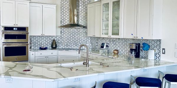 Modern white kitchen with blue stools and marble countertop.