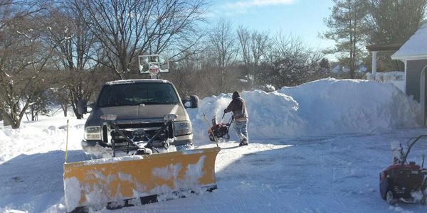 a man handling a machine or truck to clean the snow at the backyard 