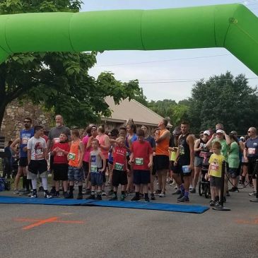 Runners ready at the starting line under a green arch.