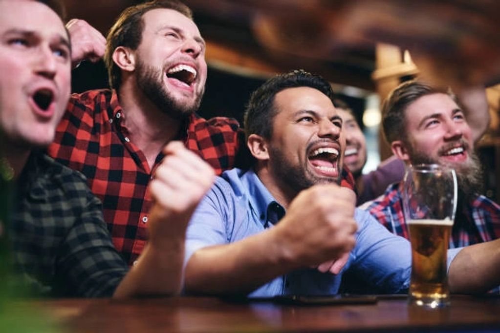 Group of men cheering and celebrating at a bar.