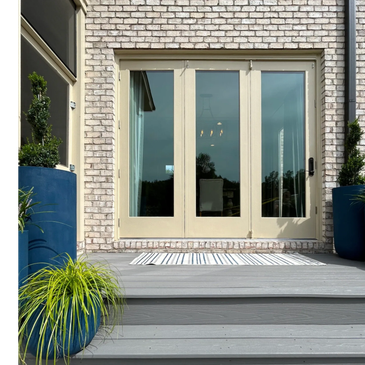 Modern beige doors with blue planters on a gray porch.
