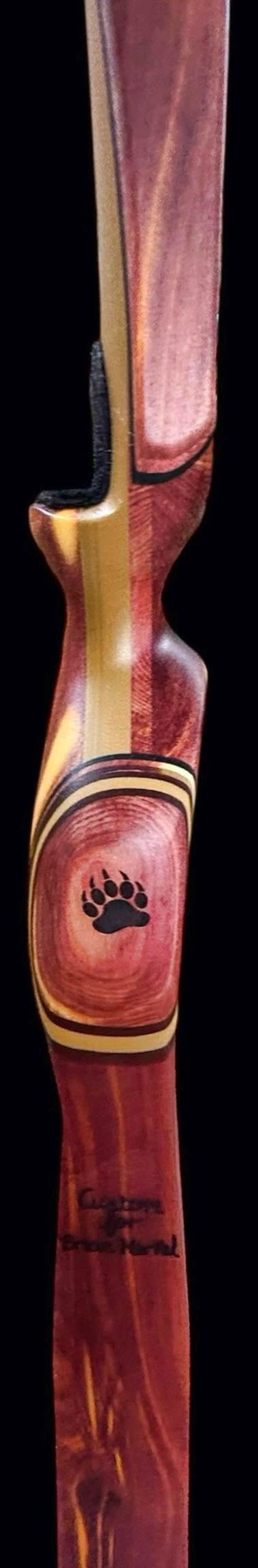 Wooden archery bow with bear paw design and inscriptions.