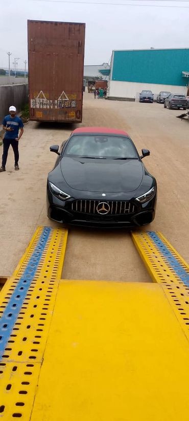 Black Mercedes-Benz car parked on a yellow ramp with a man standing nearby.