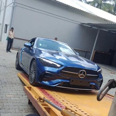 Blue Mercedes-Benz car on a yellow flatbed truck.