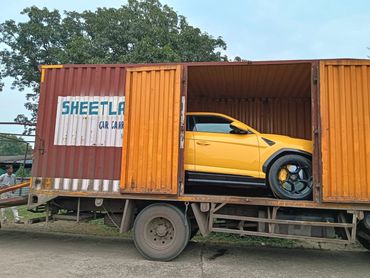 Yellow sports car inside a rusty orange shipping container on a truck.