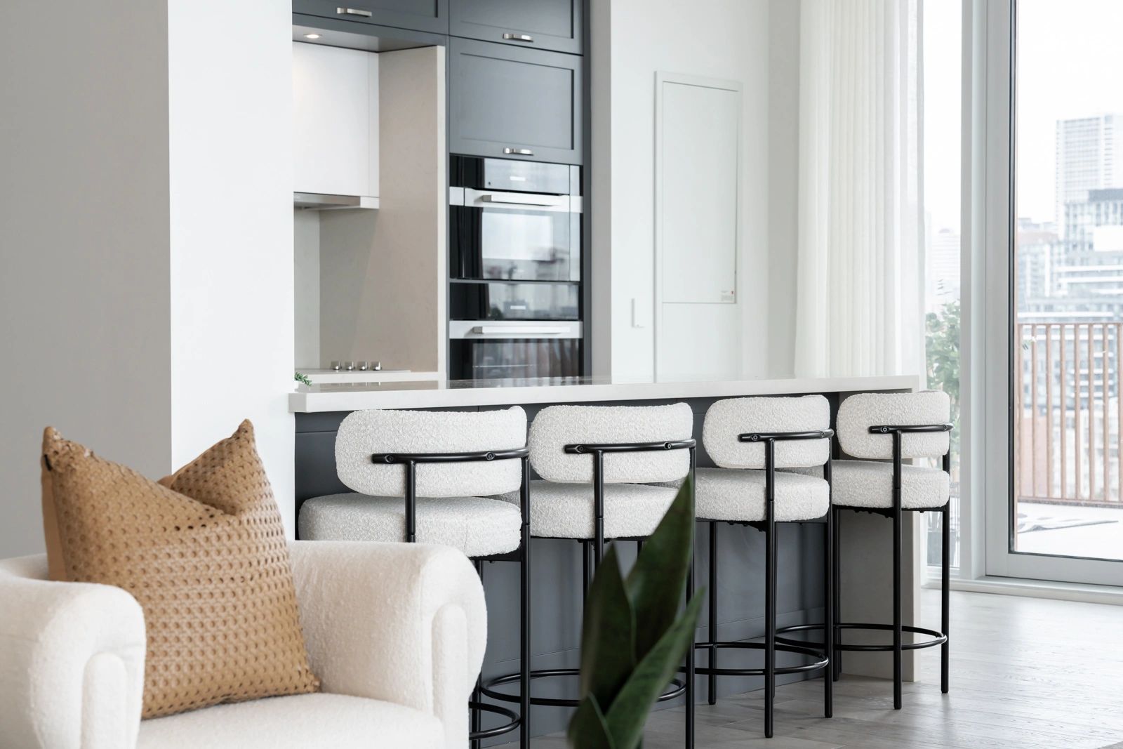 Modern kitchen with white bar stools and a cozy armchair.