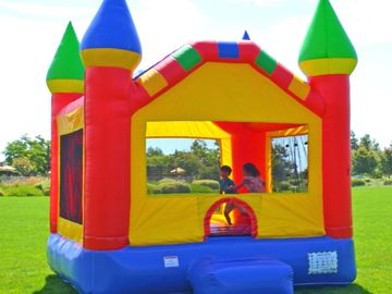 Kids playing in a colorful inflatable bounce house on a sunny day.
