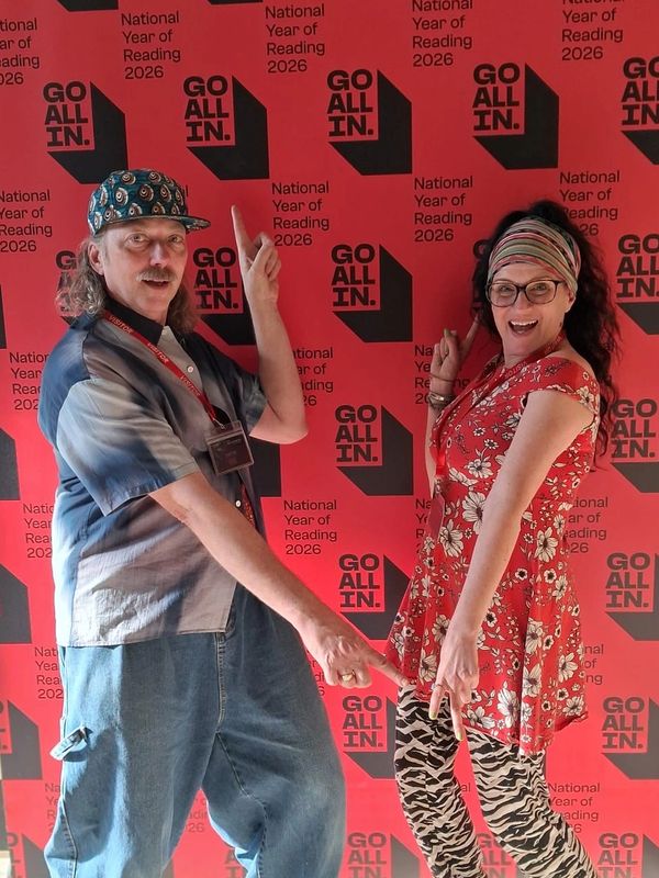 Two people posing with fingers up and down against a red backdrop.