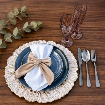 Elegant table setting with decorative plates, cutlery, and glasses on wooden surface.