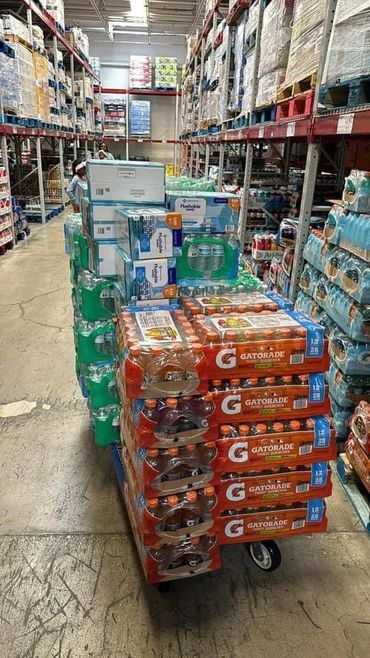 A large cart loaded with Gatorade and bottled water in a warehouse aisle.