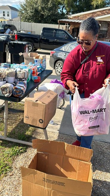 Woman donating items into a cardboard box during a community event.