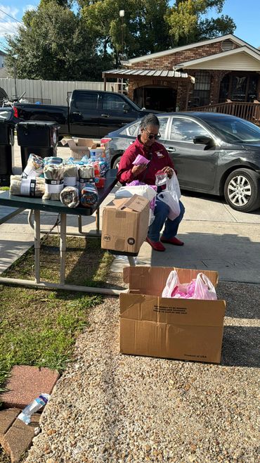 Woman sorting items at an outdoor table with blankets and supplies.