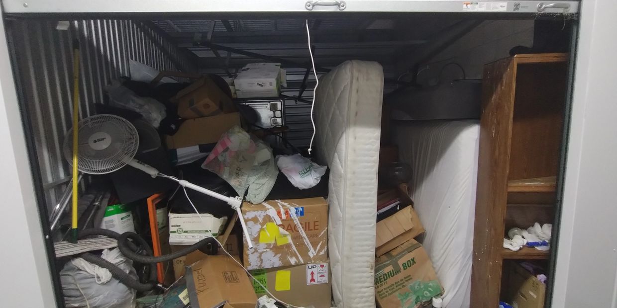 Storage unit C313 filled with boxes, furniture, and household items.