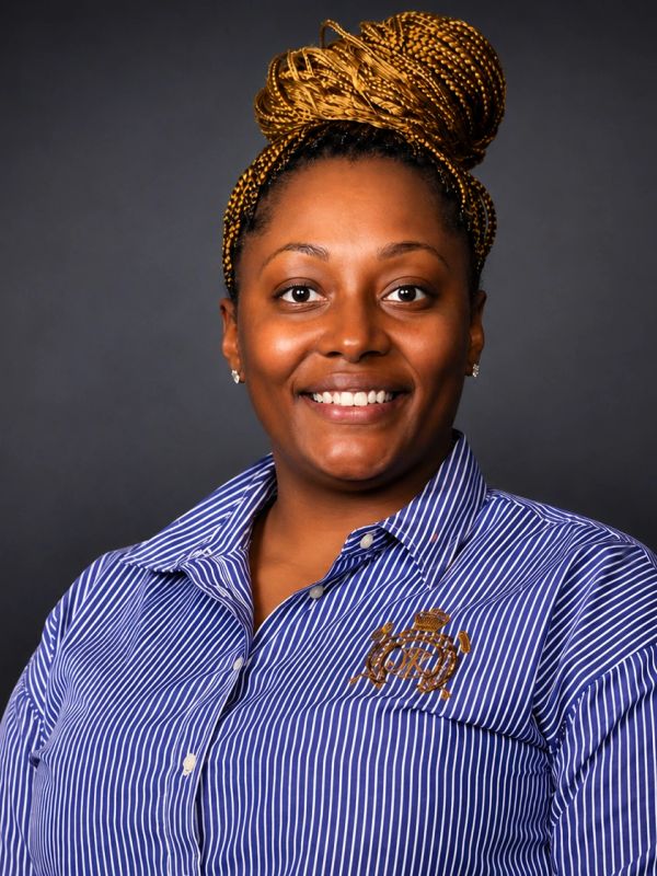 Smiling woman with braided hair bun and striped shirt.
