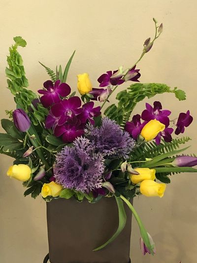 Vibrant floral arrangement with yellow roses and purple orchids.