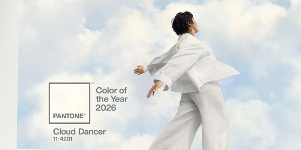 Person in white outfit against a sky backdrop with Pantone's 2026 Color of the Year Cloud Dancer.