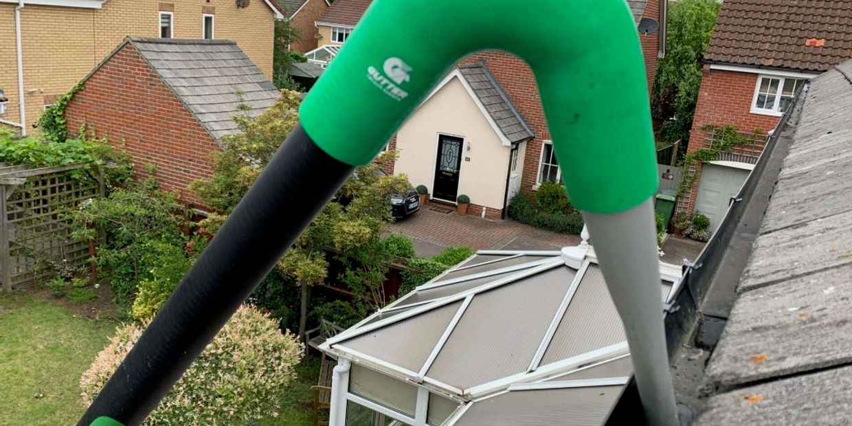 Garden tool with green handle on house roof background.