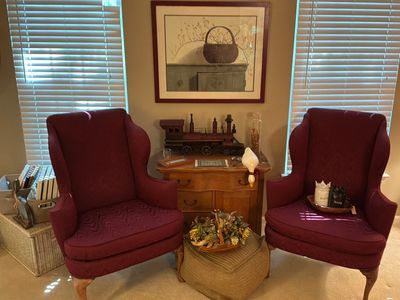 Two burgundy armchairs with wooden legs in a cozy corner.
