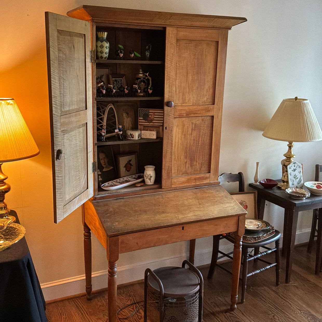 Vintage wooden cabinet with an open door filled with antiques and photos.