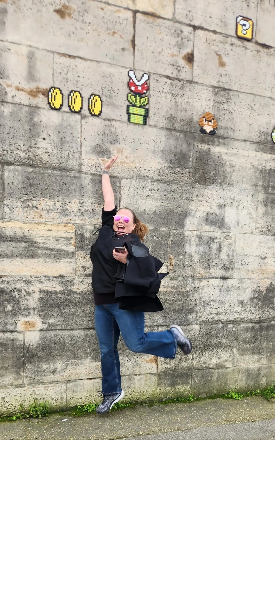 Danielle jumping for Mario coins on a wall in Paris.