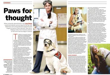 A female scientist with crossed arms is standing white a service dog in a magazine that says, "Paws 