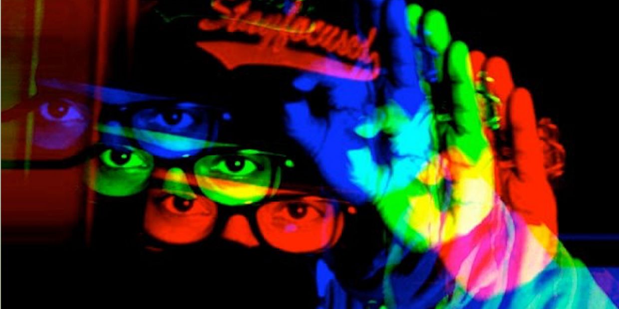 Multicolored glitch effect on a person with glasses and raised hand.