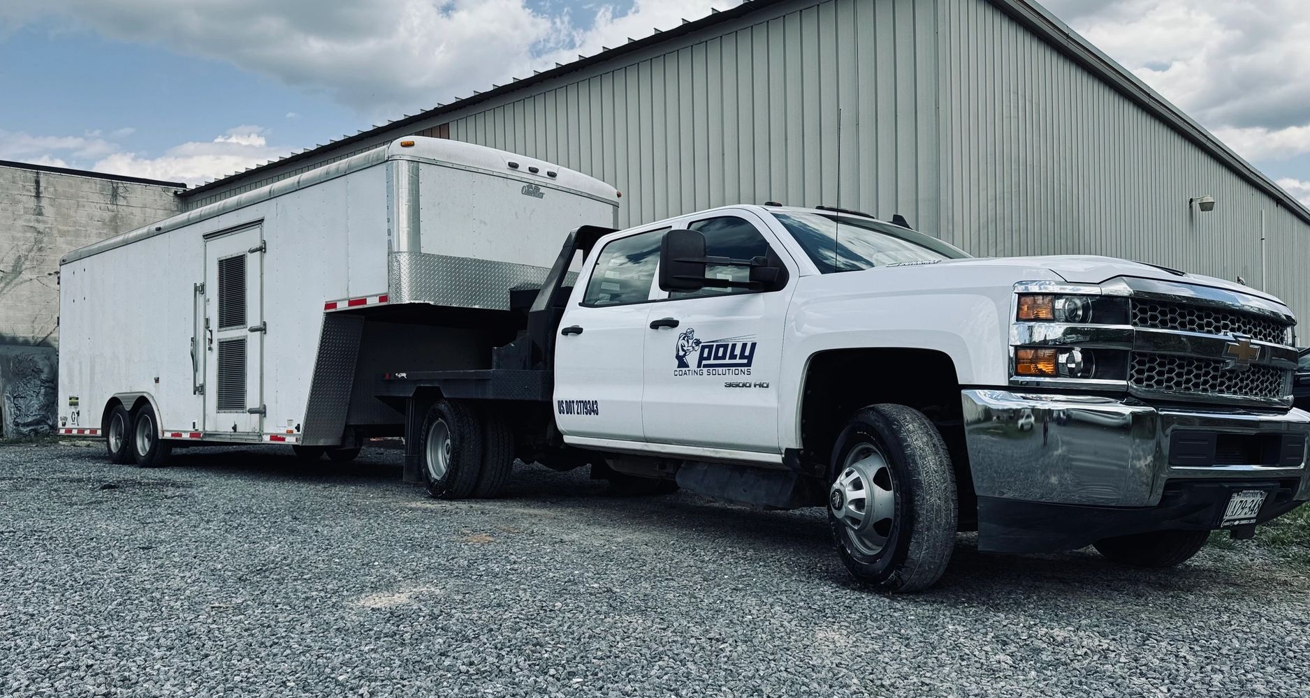 White Chevrolet truck with a large enclosed trailer in an industrial area.