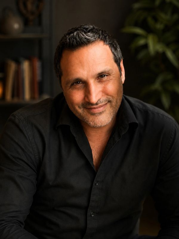 Smiling middle-aged man in a black shirt with a warm expression indoors.