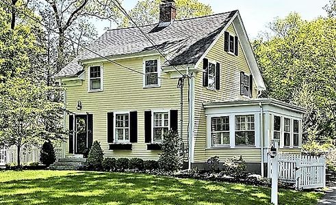 traditional two-story yellow home four-season sunroom