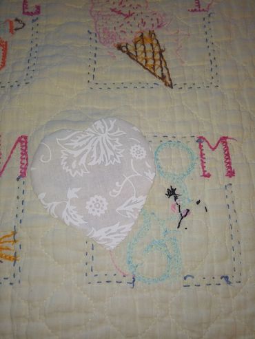 Quilt with embroidered heart, dog, and ice cream designs.