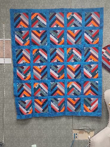 Colorful patchwork quilt with geometric patterns hung on a wall.