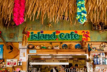 island cafe sign with shelves and counter and leis