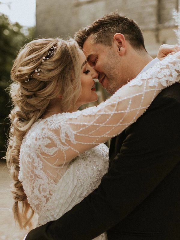 Bride with boho hairstyle kissing groom in Cornwall