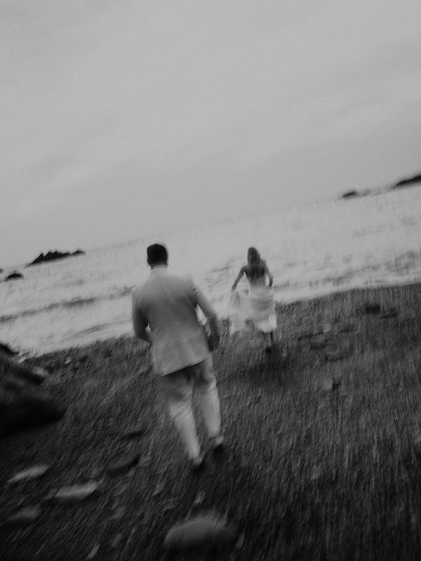 A couple walking on a beach, blurred black and white image.