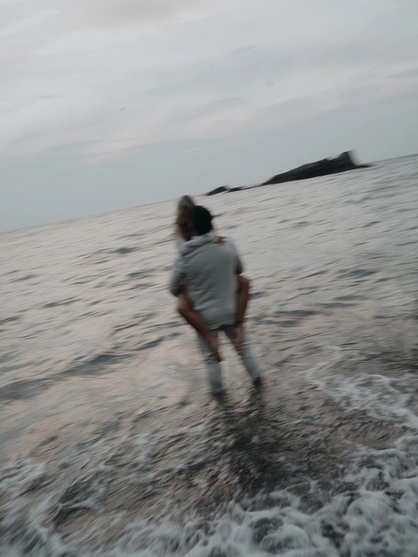 Couple by the sea, one carrying the other.