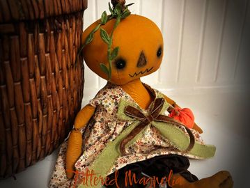 A handmade pumpkin doll with a floral dress.
