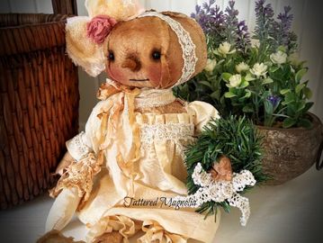 Vintage doll in a lace dress holding a small wreath.