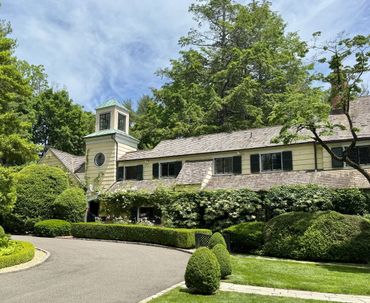 Large house with lush greenery and clear blue sky.