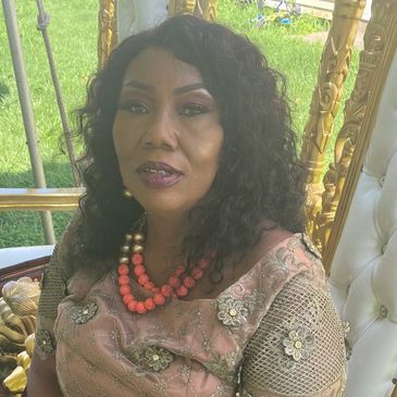Woman dressed in traditional attire with coral bead necklace and curly hair.