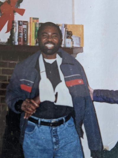 Man smiling with arm in a sling, standing indoors.