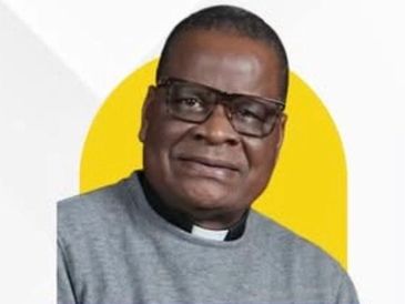 Portrait of a man wearing glasses and a clerical collar with a yellow background.