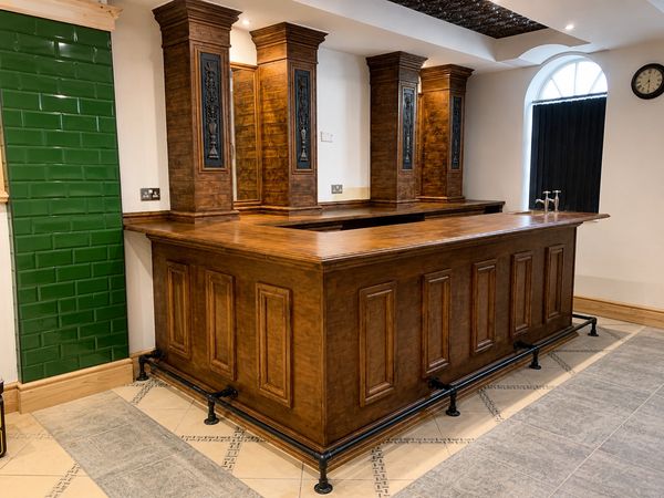 Completed bespoke timber bar with stained finish, decorative cast iron inserts and footrests