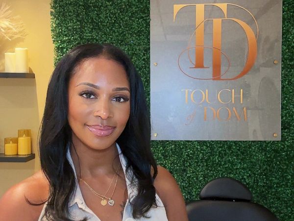 Woman smiling in front of Touch of Mom sign.